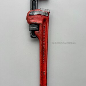 May include: A red and black pipe wrench, 14 inches long, with a toothed jaw. The wrench has the text "THE RIDGE TOOL CO. ELYRIA, OHIO U.S.A." and the Instagram handle "@moabmavericktools" printed on it.
