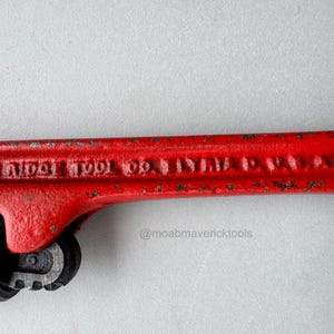 May include: Close-up of a vintage red pipe wrench. The wrench has the text "THE RIDGE TOOL CO. ELYRIA O. U.S.A. 6" embossed on the handle. The wrench is a classic tool.