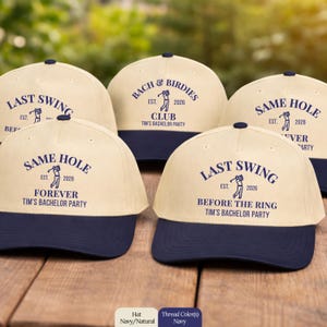 Könnte beinhalten: Eine Auswahl an marineblauen und naturfarbenen Baseballkappen mit marineblauen Texten und Grafiken. Die Kappen tragen Aufschriften wie "LAST SWING", "BACH & BIRDIES CLUB" und "SAME HOLE FOREVER". Die Kappen sind für Tims Junggesellenabschied.
