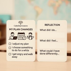 Op de afbeelding: Twee witte kaarten met tekst en illustraties worden weergegeven op een houten bureau. Eén kaart leest "MY PLAN CHANGES" met opties om het plan aan te passen, een activiteit te kiezen of weg te lopen. De andere kaart vraagt "REFLECTION" met vragen.
