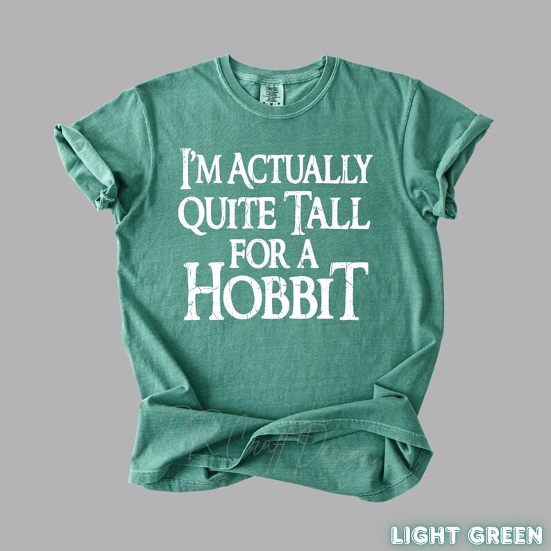 Puede incluir: Camiseta verde claro con el texto blanco "I'm Actually Quite Tall For A Hobbit". La camiseta es de cuello redondo con mangas enrolladas. La esquina inferior derecha de la camiseta tiene las palabras "Light Green".