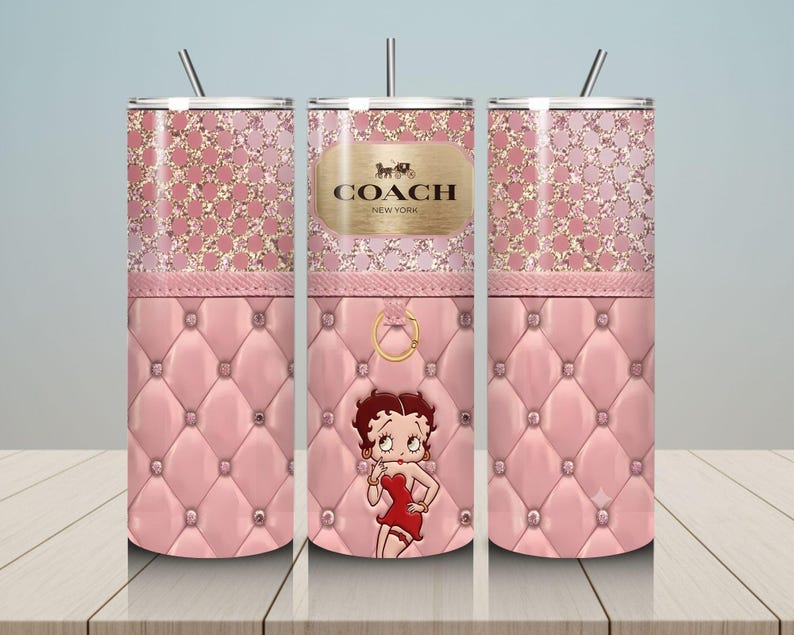 May include: A pink tumbler with a glittery top and a quilted bottom. The tumbler features a Betty Boop graphic and a gold Coach New York logo. Includes a silver straw.