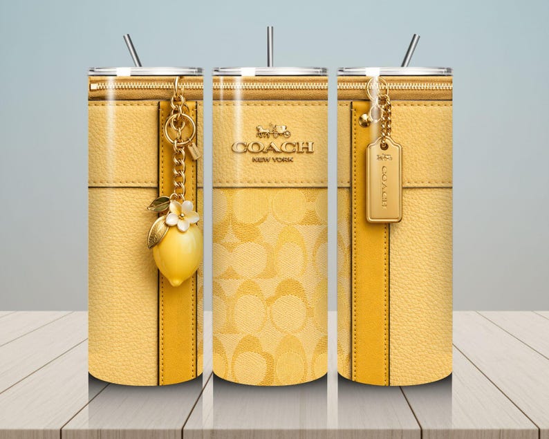May include: Yellow Coach tumbler with a zipper design, gold accents, and a lemon charm. The tumbler features the Coach New York logo and a straw. The design includes a textured leather-like appearance and a repeating pattern.