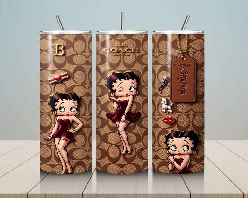 May include: A set of three stainless steel tumblers featuring a brown Coach pattern with Betty Boop illustrations. Each tumbler has a different design, including a gold letter "B", a Coach tag, and various Betty Boop themed charms. The tumblers have silver straws.