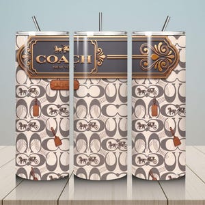 May include: A cylindrical stainless steel tumbler with a straw, featuring a beige and brown repeating pattern of horse-drawn carriages and C-shaped logos. The top section displays a dark rectangular plaque with the text COACH NEW YORK.