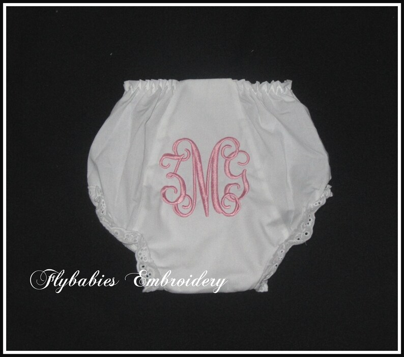 May include: White cotton baby bloomers with a pink embroidered monogram "MG" and lace trim. Flybabies Embroidery.