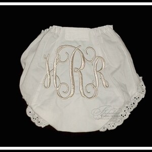 May include: White cotton baby bloomers with a lace trim and a monogrammed "HPR" in a script font.