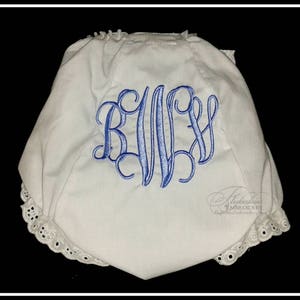 May include: White cotton baby bloomers with a blue embroidered monogram "R.I.W." and white lace trim.
