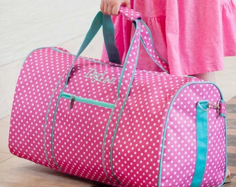 May include: Pink polka dot duffel bag with a teal zipper and trim. The bag has the name "Dylan" embroidered on the front.