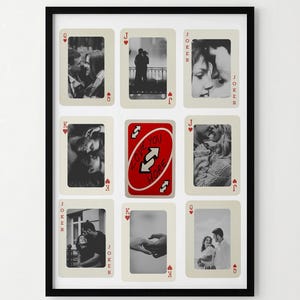 May include: A black framed wall art piece featuring nine playing card-shaped photo frames. Eight frames contain black and white photos, while the central frame displays a red Uno card. The frame is rectangular and hangs on a white wall.