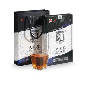 May include: A black and white gift bag and a rectangular box of Baishaxi 1939 Tian Fu Cha tea, both featuring Chinese text and a net weight of 1kg. A clear, square glass cup filled with dark amber tea sits in front of the packaging.