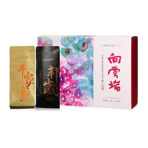 May include: A tea set featuring two tea pouches and a box. The pouches are gold and black, with Chinese characters and the years 2022 and 2019. The box has a floral design and Chinese text.