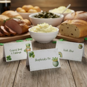 May include: A wooden table displays a St. Patrick's Day feast, including corned beef, cabbage, mashed potatoes, and bread. Three place cards read "Corned Beef & Cabbage", "Shepherd's Pie", and "Irish Stew", with related illustrations. Green shamrocks are scattered around.