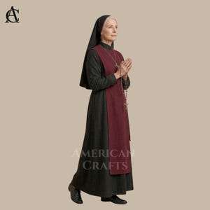 May include: A woman in a traditional nun's habit, featuring a black veil and a long, dark gray dress with a burgundy apron-like overlay. The image includes the text "AMERICAN CRAFTS". She is holding a rosary.