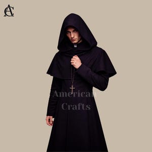 May include: A black hooded cloak with a matching cape and long sleeves. A silver cross necklace hangs from the neck. The text "American Crafts" is visible on the garment. The outfit is suitable for cosplay or historical reenactment.