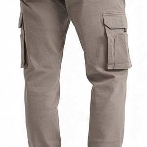 Peut inclure: Pantalon cargo de couleur taupe avec plusieurs poches, dont deux poches cargo lat&eacute;rales et deux poches arri&egrave;re. Le pantalon a une fermeture boutonn&eacute;e et une coupe d&eacute;contract&eacute;e. Le mod&egrave;le porte des chaussures marron. Le pantalon est en tissu r&eacute;sistant.