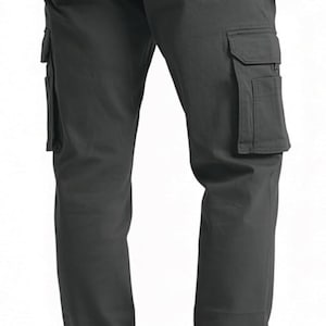 Peut inclure: Pantalon cargo gris fonc&eacute; avec plusieurs poches sur les c&ocirc;t&eacute;s et &agrave; l'arri&egrave;re. Le pantalon a une coupe droite et est fabriqu&eacute; dans un tissu r&eacute;sistant. Le mod&egrave;le porte des chaussures marron.