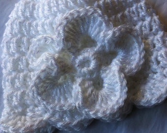 May include: White crocheted hat with a large flower design. The hat is made with sparkly yarn.