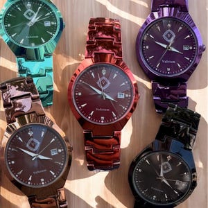 May include: Six colorful wristwatches with metallic bands and watch faces. The watches are in shades of green, red, purple, brown, and black. Each watch face has the brand name "Valirium" and a date display.