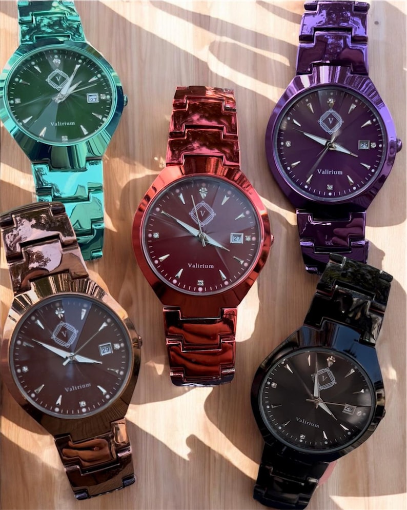 May include: Six colorful wristwatches with metallic bands and watch faces. The watches are in shades of green, red, purple, brown, and black. Each watch face has the brand name "Valirium" and a date display.