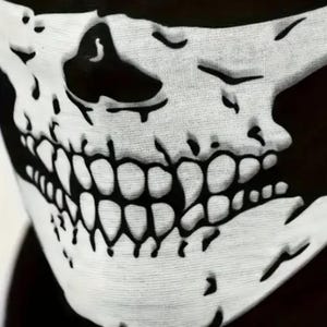 May include: A black and white skull face mask. The mask has a detailed skull design with prominent teeth, eye sockets, and a nose cavity. The white skull graphic is set against a black background, creating a high-contrast, spooky effect.