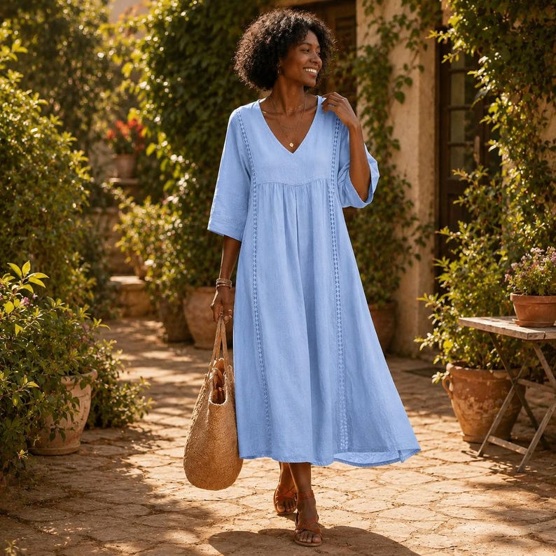 May include: A light blue midi dress with a V-neckline, three-quarter length sleeves, and vertical lace trim detailing along the bodice. The dress features a loose, flowing silhouette and is paired with a large, textured tan woven tote bag.