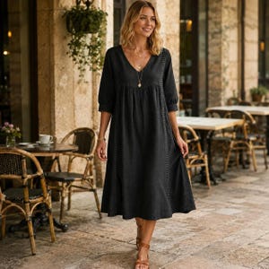 May include: A black midi-length dress featuring a V-neckline, three-quarter length sleeves, and vertical lace trim detailing along the bodice. The garment has a loose, flowing silhouette with a gathered waistline and a simple, solid-colored design.
