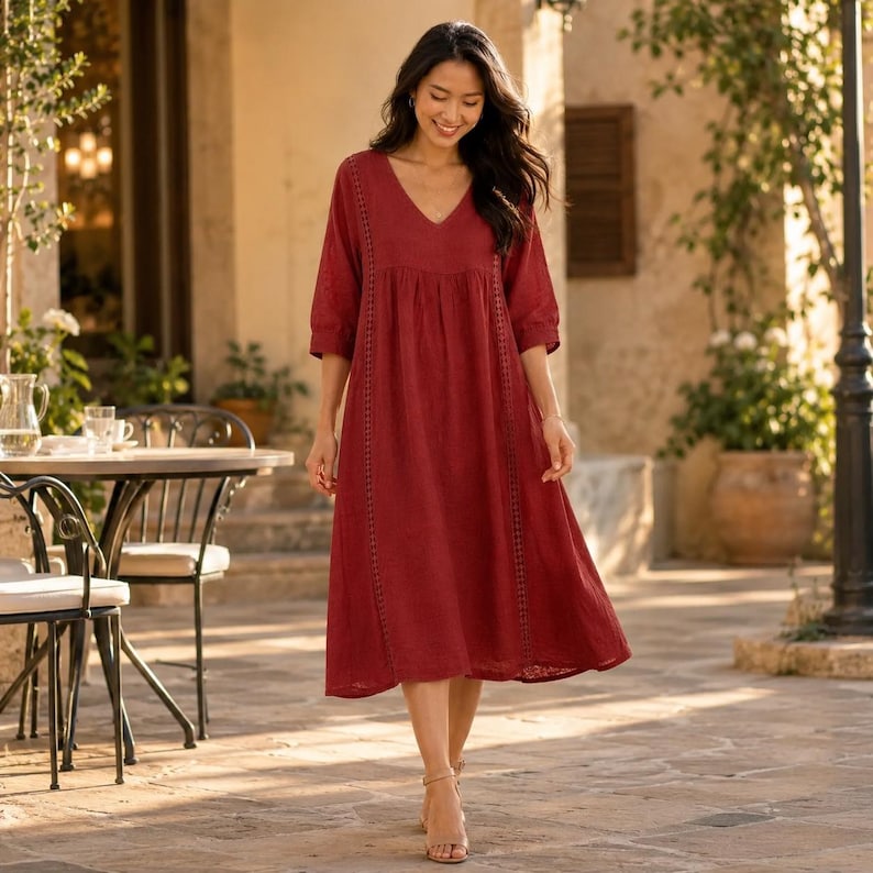 May include: A deep red midi dress featuring a V-neckline, three-quarter length sleeves, and vertical lace trim detailing along the front bodice. The garment has a loose, flowing silhouette that falls below the knees with a gathered waistline.