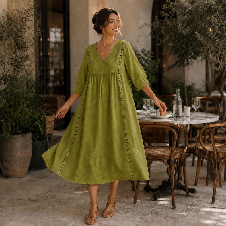 May include: A midi-length olive green dress featuring a V-neckline, three-quarter length sleeves, and vertical lace trim detailing running down the front. The garment has a loose, flowing silhouette with a gathered waistline and a flared skirt.