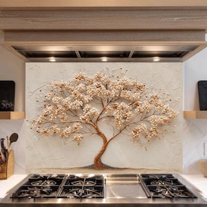 May include: A kitchen backsplash features a handcrafted tree sculpture with a brown trunk and branches adorned with cream-colored blossoms. The artwork is set against a textured, off-white background, above a stainless steel gas range.