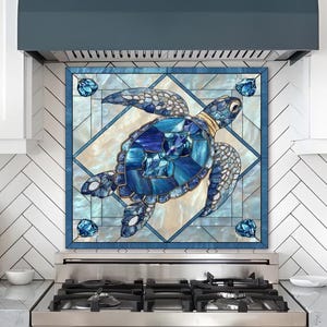 May include: A blue and white decorative kitchen backsplash featuring a stained glass design of a sea turtle. The turtle is composed of various shades of blue, with a gold-colored neck. The backsplash is framed by a blue border.