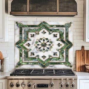 May include: A decorative kitchen backsplash featuring a star-shaped design with green and gold accents. The backsplash is set against a white marble background and is installed above a stainless steel gas range. The kitchen has white cabinets and a dark range hood.