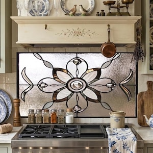 May include: A kitchen scene featuring a stained glass window with a floral design. The kitchen has a stove, shelves with plates, and a basket of apples. A copper pan hangs above the stove, and a scale sits on a shelf.