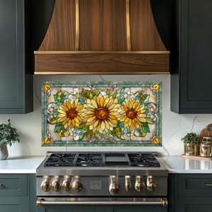 May include: A stained glass kitchen backsplash featuring three large sunflowers with yellow petals and brown centers. The sunflowers are surrounded by green leaves and decorative swirls, set against a light background with a green border.