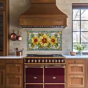 May include: A stained glass panel featuring three sunflowers with yellow petals and brown centers, surrounded by green leaves and a teal border. The panel is mounted above a burgundy and gold stove in a kitchen setting.