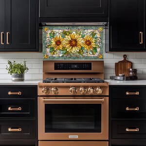May include: A kitchen with black cabinets, a copper-colored stove, and a decorative backsplash featuring a stained-glass design of sunflowers. The stove has multiple burners and a digital display. A plant in a pot sits on the countertop.