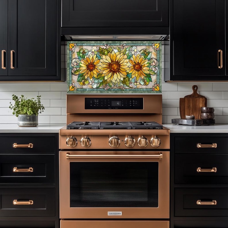 May include: A kitchen with black cabinets, a copper-colored stove, and a decorative backsplash featuring a stained-glass design of sunflowers. The stove has multiple burners and a digital display. A plant in a pot sits on the countertop.