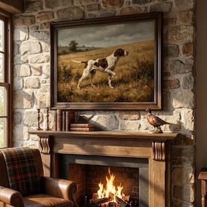 May include: A framed oil painting of a brown and white pointer dog standing in a grassy field, displayed above a wooden fireplace mantel. The mantel holds three leather-bound books, two brass candlesticks, and a decorative pheasant figurine.
