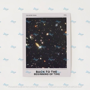 Puede incluir: Una impresión rectangular que presenta una imagen del espacio profundo con numerosas galaxias y estrellas. La impresión tiene un borde blanco con el texto "Interstellar Series" y "1996" en la parte superior, y "BACK TO THE BEGINNING OF TIME" en la parte inferior.