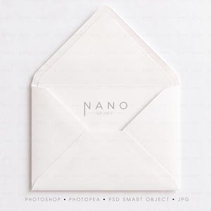 Op de afbeelding: Een witte papieren envelop met een open driehoekige klep, voorzien van de tekst NANO ARCHIVE gedrukt in een dun, donkergrijs schreefloos lettertype op het binnenpaneel. De envelop heeft een klassiek ontwerp met een puntige klep.