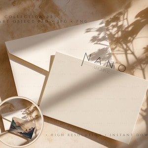 Peut inclure: Un ensemble de papeterie ivoire avec une enveloppe et une carte, avec le texte "NANO ARCHIVE" et "COLLECTION 023". Une petite carte avec une peinture de paysage est dans un cadre circulaire. La scène est éclairée par la lumière du soleil.