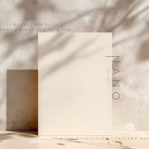 以下が含まれることがあります： テクスチャード加工された壁に立てかけられた、クリーム色の紙のミニマリストモックアップ。「COLLECTION 01」、「SMART OBJECT PSD JPG PNG」、「NANO ARCHIVE」、「HIGH RESOLUTION」、「INSTANT DOWNLOAD」の文字が見える。