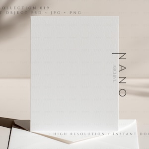 May include: A white card with a textured surface stands upright, slightly angled, atop a white envelope. The card is the focal point, with the text "COLLECTION 019" and "NANO ARCHIVE" visible. The background is a soft, neutral tone.