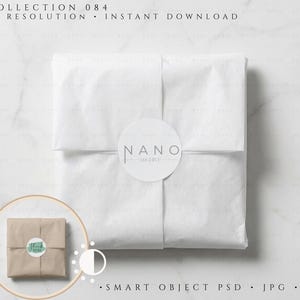 May include: A square package wrapped in white paper, sealed with a round sticker that reads "NANO ARCHIVE". The image includes a smaller, wrapped package in a brown paper with a green and white sticker. The text "COLLECTION 084" is at the top.