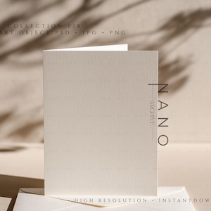 Puede incluir: Una tarjeta plegada, de color blanquecino, con un sobre a juego, presentada sobre una superficie neutra. La tarjeta es texturizada y la imagen incluye el texto "COLLECTION 018" y "NANO ARCHIVE". La estética general es minimalista y elegante.