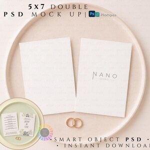 Puede incluir: Una maqueta PSD doble de 5x7 con dos tarjetas rectangulares blancas en blanco sobre una bandeja circular. Una tarjeta muestra el texto NANO ARCHIVE. Dos anillos dorados se colocan entre las tarjetas. Un recuadro circular muestra una invitación.
