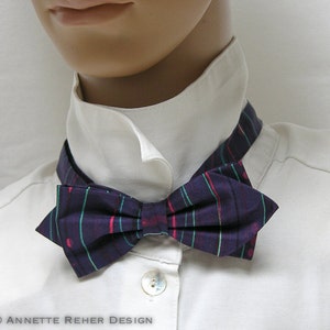 Peut inclure: Un nœud papillon à carreaux violets avec des accents rouges et verts est présenté sur une chemise blanche à col. Le nœud papillon est noué et positionné autour du cou, un accessoire classique.