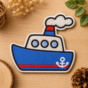May include: An embroidered iron-on patch shaped like a steamship. The boat features a blue hull with a red stripe and a white anchor, a white cabin with three light blue portholes, a blue and red smokestack, and a white cloud of smoke.