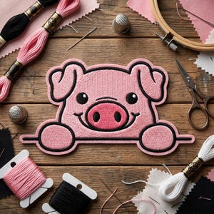 May include: A pink embroidered pig patch with a black outline, smiling, with black eyes and a pink snout. The patch is surrounded by embroidery supplies: thread spools, needles, thimbles, scissors, and an embroidery hoop. The items are arranged on a wooden surface.