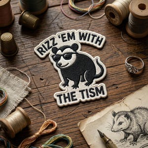 May include: Embroidered patch featuring a black and white opossum wearing sunglasses, with the text "Rizz 'em with the Tism". The patch is surrounded by sewing supplies on a wooden surface, including spools of thread and thimbles.